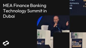 Speaker with Microphone on Stage During the Mea Finance Banking Technology Summit in Dubai Against a Dark Geometric Backdrop