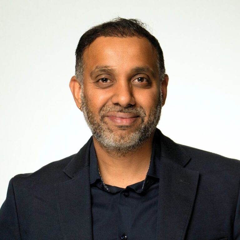 Management - Arvind Ramachandran | Smartstream | Smartstream Smiling Man in a Dark Blazer and Navy Shirt Poses for a Portrait Against a Light Background